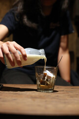 Pouring milk in to a cup of coffee ice