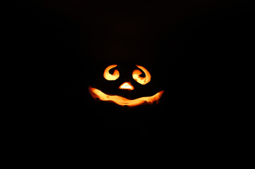 glowing smiling face Halloween pumpkin, candle holder, isolated on night dark black background