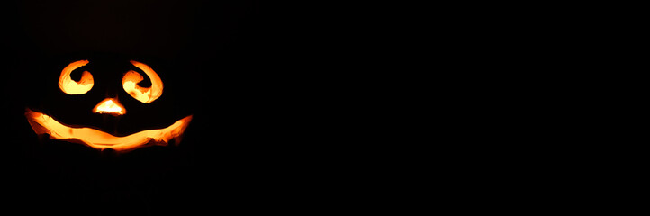 Fototapeta premium glowing smiling face Halloween pumpkin, candle holder, isolated on night dark black background. space for text. banner