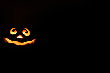 Fototapeta premium glowing smiling face Halloween pumpkin, candle holder, isolated on night dark black background. space for text