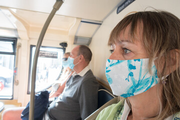 Head shot of a lady wearing a face mask on a bus. Image
