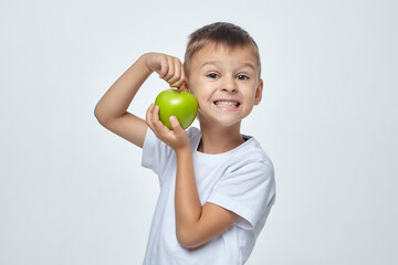 cute boy is holding a green Apple in front of his face. photo session in the Studio on a white background