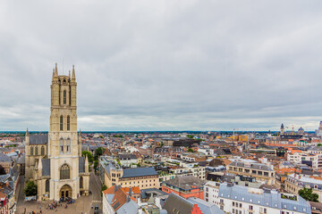 Fototapeta na wymiar Aerial view of the Ghent cityscape, the facade of St Bavo Cathedral with its imposing tower surrounded by houses and buildings in the city center, cloudy day with a cloud covered sky in Belgium
