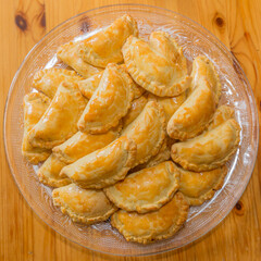 Delicious ground beef patties fresh out of the oven in a glass plate on a wooden surface. Traditional food in Latin American cuisine. Top view or flat lay