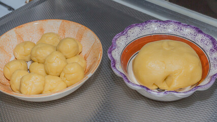 Ball and balls of fresh raw dough in brown and purple ceramic bowls on a metal base, preparation of tortillas or empanadas in traditional Mexican cuisine