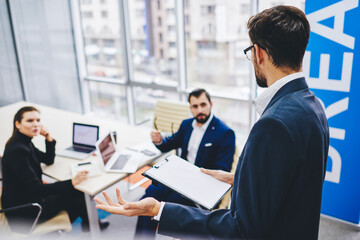 Blurred male and female colleagues sitting at table desktop and listening business strategy during training experience with formally dressed leader, Caucasian partners brainstorming in office