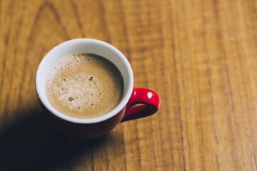 Red espresso cup with coffee on wooden table. High quality photo