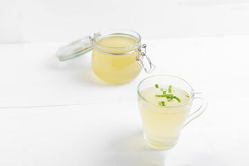 Homemade bone broth with leek in glass cup