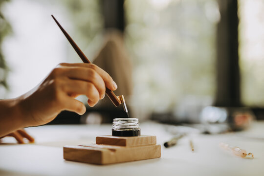 Artist holding old-fashioned fountain pen for calligraphy writing.