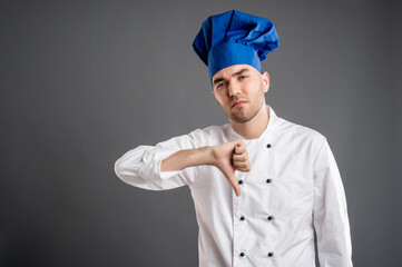 Young male dressed in a white chef suit showing showing dislike