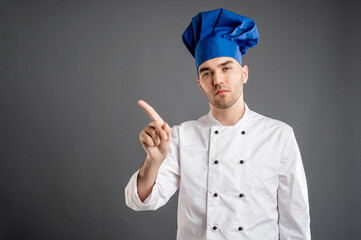 Young male dressed in a white chef suit showing no with his finger