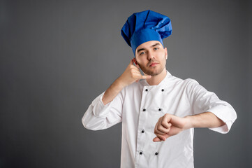 Young male dressed in a white chef suit showing it's time gesture