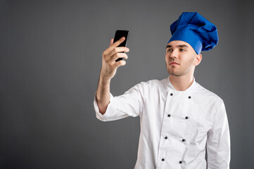 Young male dressed in a white chef suit taking selfie photography