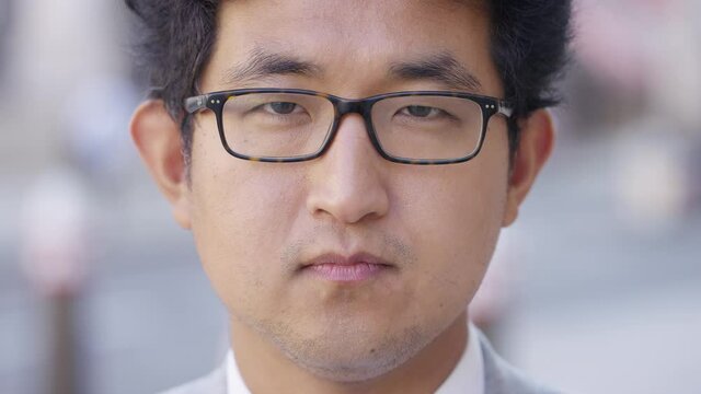 Close up portrait of young Asian man looking straight to camera with a blank expression