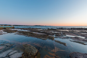 Rocky seascape with clear sunrise sky.