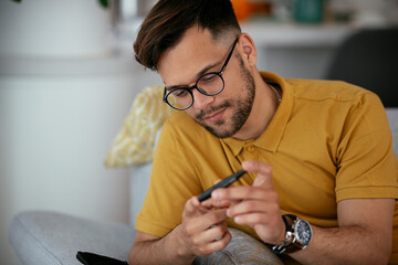 Diabetic man taking blood sample with lancet pen at home.