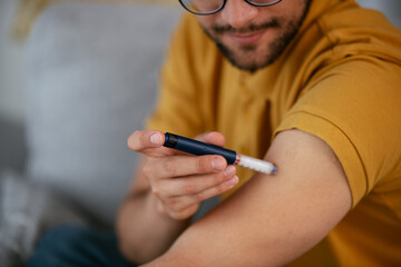 Young man giving himself an insulin shot at home.