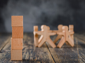 Business success and teamwork concept with wooden figures of people, cubes on wooden and foggy background side view.