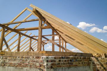 Aerial view of unfinished house with wooden roof frame structure under construction.