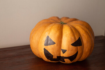 pumpkin decorated like a jack lamp, sitting on the brown table. happy Halloween