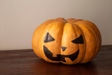 pumpkin decorated like a jack lamp, sitting on the brown table. happy Halloween