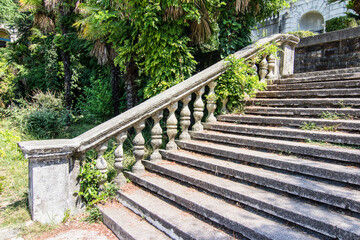 Fototapeta na wymiar Ancient staircase with stone balusters on a background of green vegetation