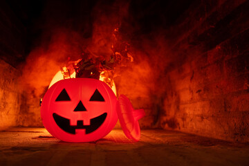 Creepy and scary smiling pumpkin with a red moon behind, dry grass and smoke scene in a stone background for halloween