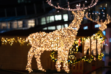 Blurred lights of christmas installation - defocused lights of deer on night city background. Christmas deer installation in Milan