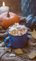 Autumn background with dry leaves, blue cup of coffee. Knitted background, pumpkins, October, November. Autumnal atmosphere. Autumn season.