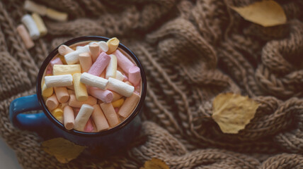 Autumn background with dry leaves, blue cup of coffee. Knitted background, pumpkins, October, November. Autumnal atmosphere. Autumn season.
