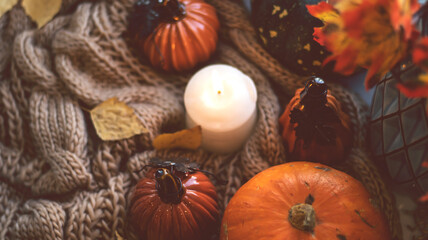 Autumn background with dry leaves, blue cup of coffee. Knitted background, pumpkins, October, November. Autumnal atmosphere. Autumn season.