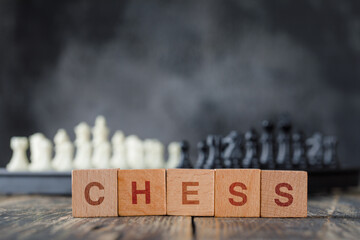 Business strategy concept with chessboard and figures, wooden cubes on foggy and wooden background side view.