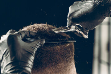 Cropped shot of barber cutting hair of customer with scissors