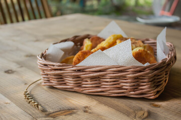 ruddy pastries lie in a wicker square basket on napkins on a wooden table under the sun. The concept of a delicious healthy Breakfast in the village
