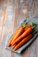 A stack of fresh carrots on country village table with kitchen towel, top view, side view