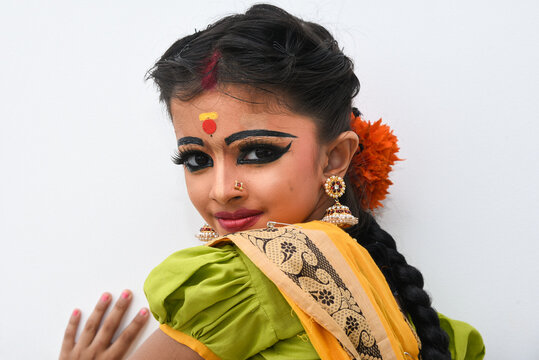 Beautiful Indian girl or women or kid wearing sari or saree as Indian folk, classical  dancer in dance pose wearing traditional dress for females in Kerala,  India. wearing ornaments and makeup. Stock