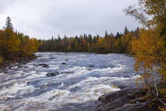The Jacques-Cartier River seen flowing between wooded banks during a cloudy Fall afternoon, Shannon, Quebec, Canada
