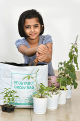 Cute young Indian girl kid in her organic vegetable garden. Cute Little girl taking care city balcony terrace garden. gardening farming in grow bag , Kerala India . Asian child . Go green save earth. 