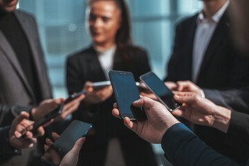 group of young business people with smartphones standing in a circle