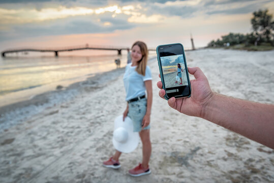 woman taking photo on smartphone on the beach