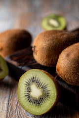 Close up of sour kiwi fruit, sliced and whole ones on wooden cutting board