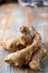 Single ginger root in peel, close up on wooden background