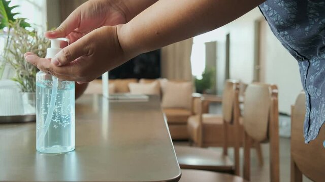 4k dolly shot alcohol gel bottle with hand pressing to clean for cirus protecting on dining table home safety new normal health and protection lifestyle