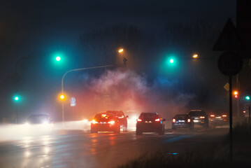 Crossing with luminous traffic lights in foggy night and steam.