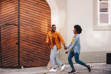 Young attractive hipster african american couple holding hands and walking on the street downtown.