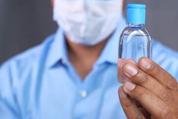 man in face mask holding sanitizer gel 