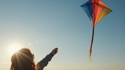 Red-haired woman flying kite against blue sky at sunset on sunny day in summer wheat field, playing with wind of an orange sunset on day lens flares wind turbines in summer slow motion. Relax. Freedom