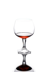 Glass of cognac with reflection on a white background.  Alcohol consumption.