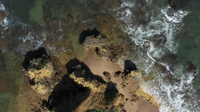 AERIAL DIRECTLY ABOVE A Rocky Point Along A Coastline On A Sunny Day