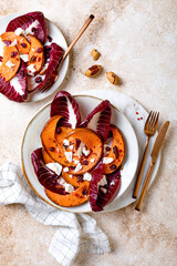 Roasted pumpkin salad with radicchio leaves, feta cheese, nuts and cranberries. Thanksgiving side dish dinner recipe. Healthy seasonal fall or autumn food